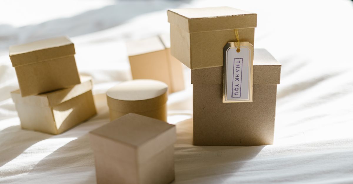 Cardboard gift boxes on a bed with thank you tag in natural light, perfect for product mockups.