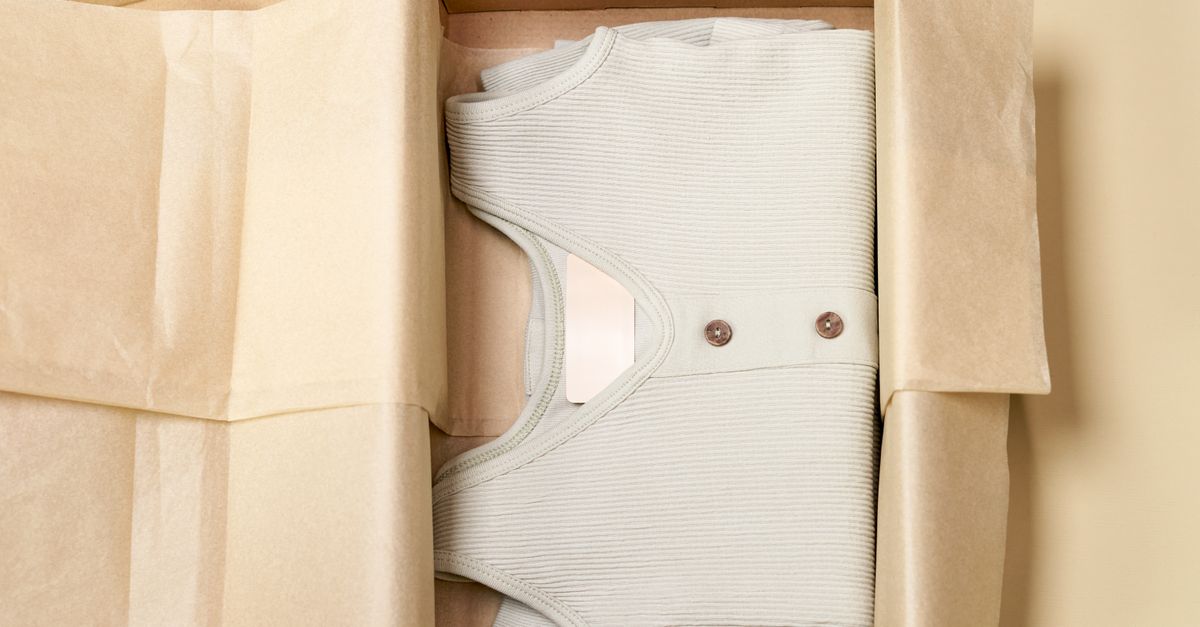 Minimalist packaging showcases a ribbed beige garment neatly folded inside a cardboard box.