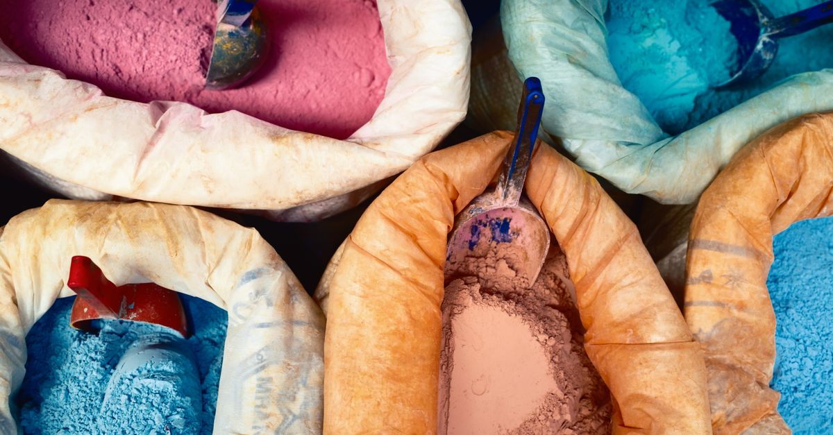 Vibrant colored dye powders in sacks at a market, showcasing traditional craftsmanship.