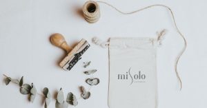 Organic cosmetic packaging with natural elements and stamp on white background.
