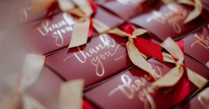 A close-up of beautifully wrapped red gift boxes with 'Thank you' tags and golden ribbons.