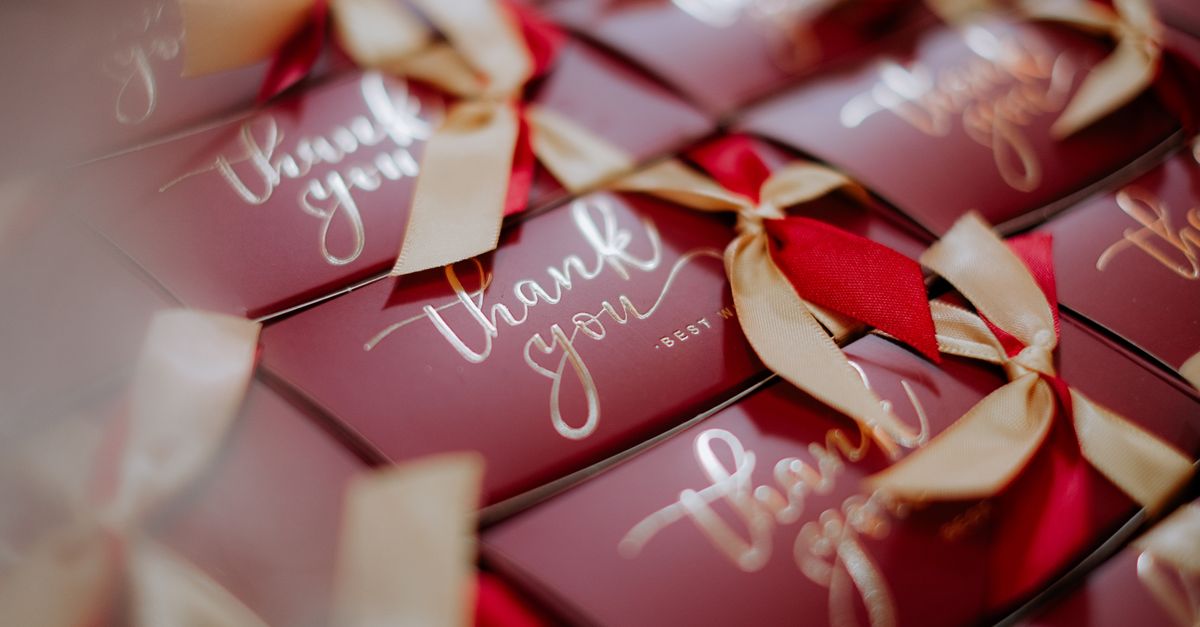 A close-up of beautifully wrapped red gift boxes with 'Thank you' tags and golden ribbons.