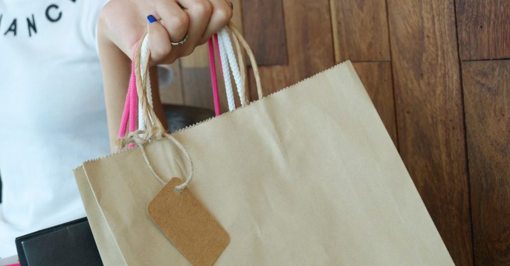 Close-up of a woman holding shopping bags with wooden background.