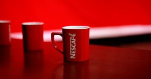 Bright red coffee mug featuring bold branding on a clean studio background.