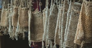 A collection of handcrafted jute bags hanging in a market, showcasing traditional craftsmanship.