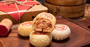 Close-up of Chinese pastries on a wooden tray, showcasing flaky texture and insert packaging.