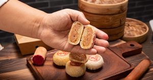Close-up of traditional Chinese mooncakes with a hand showing the inner filling.