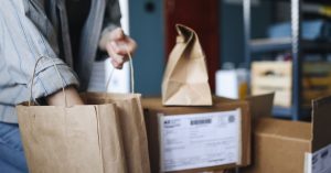 Woman sorting parcels and paper bags in a home setting, showcasing online shopping and delivery.