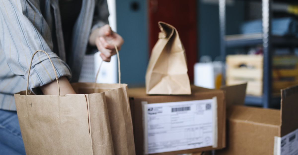 Woman sorting parcels and paper bags in a home setting, showcasing online shopping and delivery.