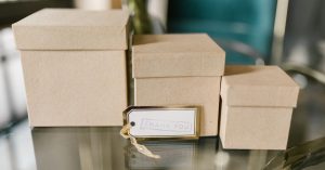 Three brown cardboard boxes on a glass table with a tag reading 'Thank You.', perfect for gifting concepts.