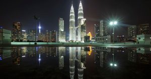 Beautiful view of Kuala Lumpur's skyline featuring the iconic Petronas Towers at night with city lights and reflections.
