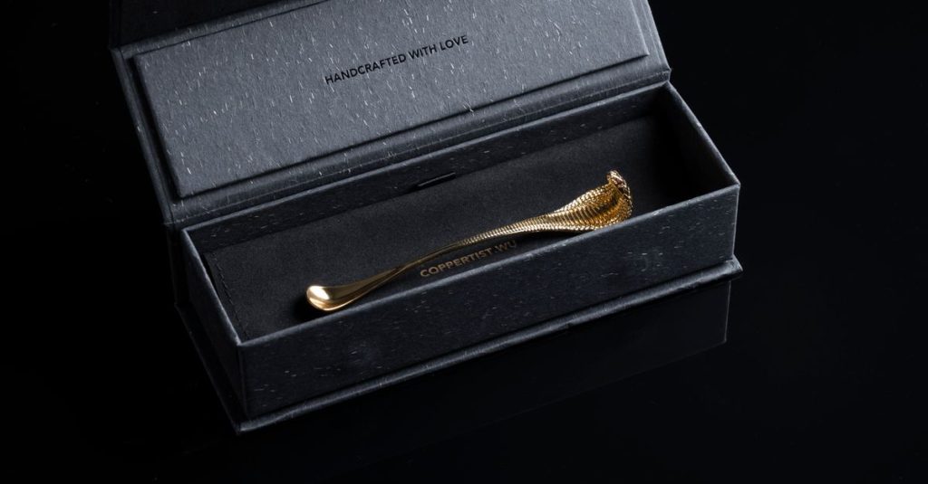 Close-up of a handcrafted golden snake-themed spoon in a black luxury box.