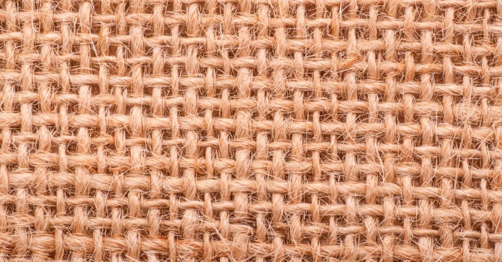 Close-up of a rough jute weave texture showing intricate fibrous pattern.