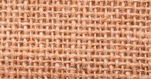 Close-up of a rough jute weave texture showing intricate fibrous pattern.