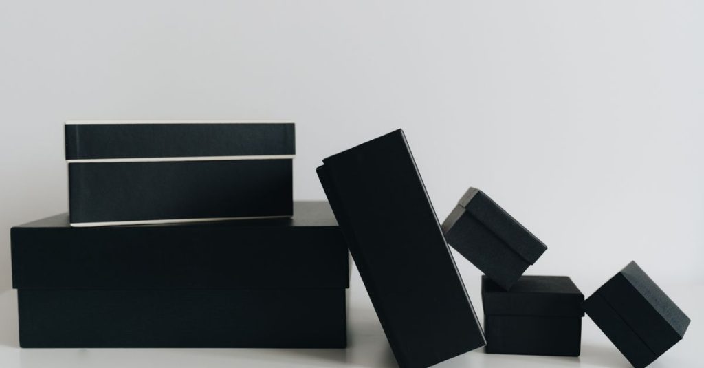A minimalist display of black gift boxes of varying sizes against a white background.