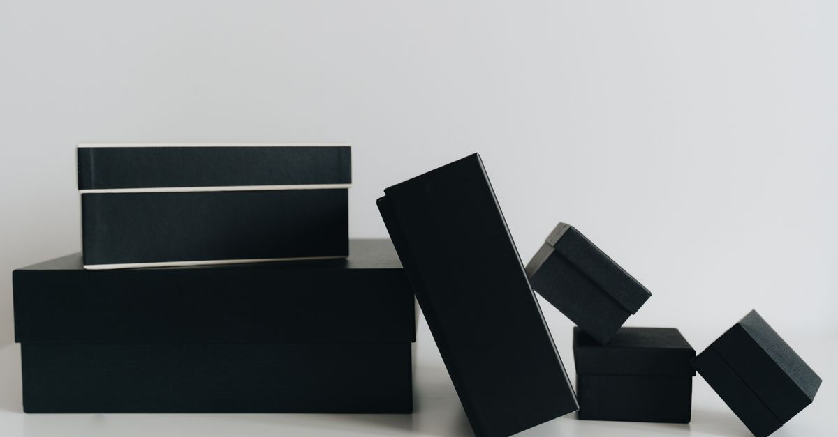 A minimalist display of black gift boxes of varying sizes against a white background.