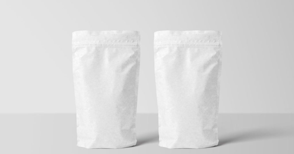 Two white paper stand-up pouches for packaging mockup on a clean surface.
