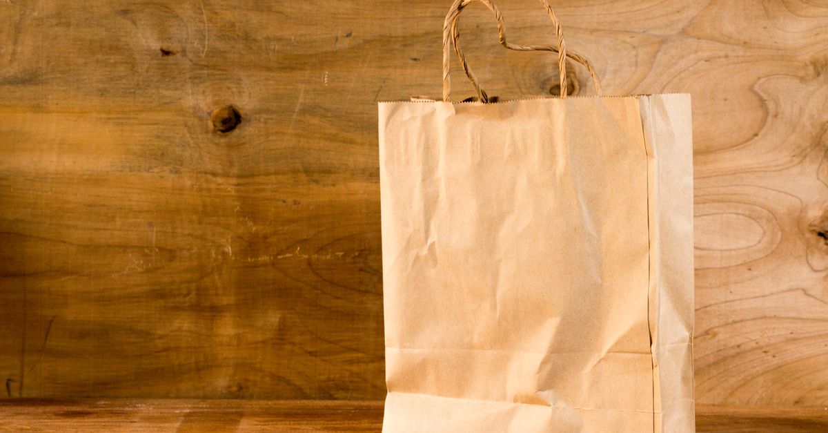 Close-up of a brown paper bag with handles on a wooden surface, offering warm earthy tones.