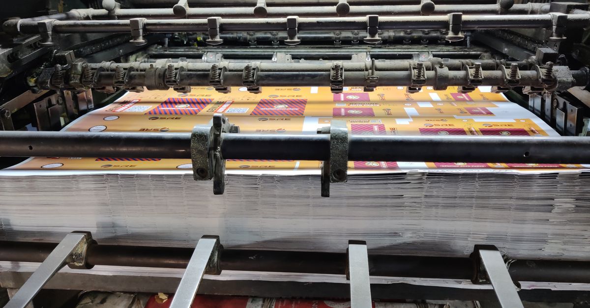 Close-up of an industrial printing machine processing paper sheets in a factory setting.