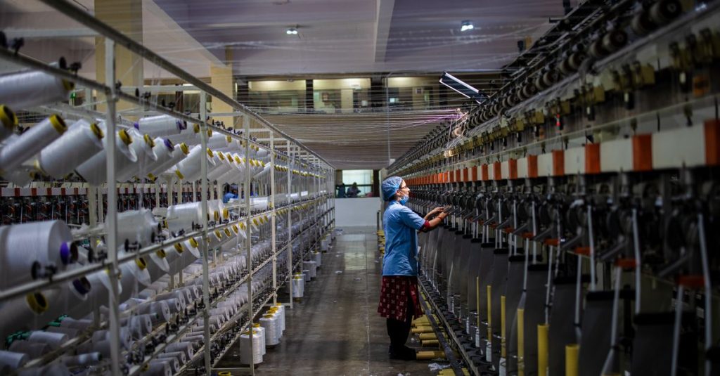 Textile factory worker monitoring machinery. Industrial and manufacturing setting.