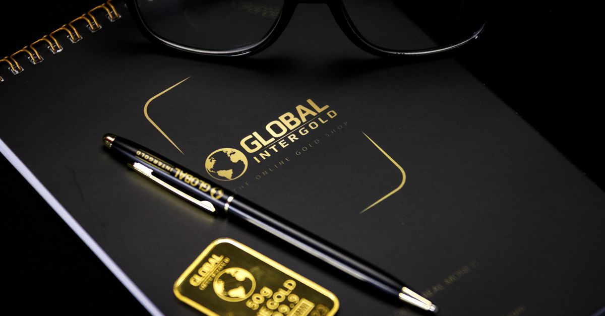 An elegant setup with a notebook, pen, and gold bar, embodying luxury and style.