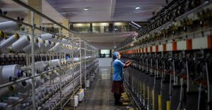 Textile factory worker monitoring machinery. Industrial and manufacturing setting.