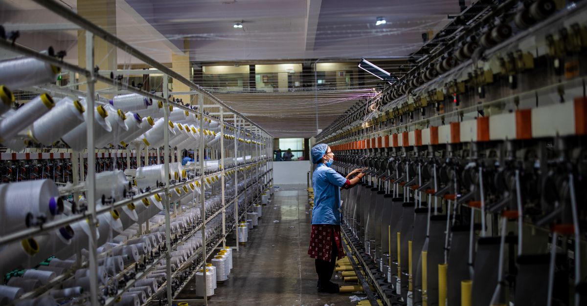 Textile factory worker monitoring machinery. Industrial and manufacturing setting.